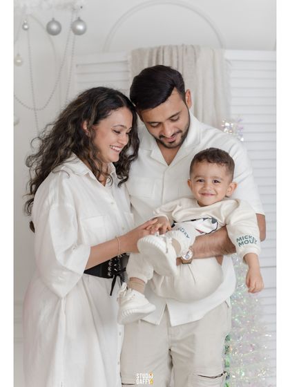 A happy family of three, their smiles as bright as the Christmas decorations.