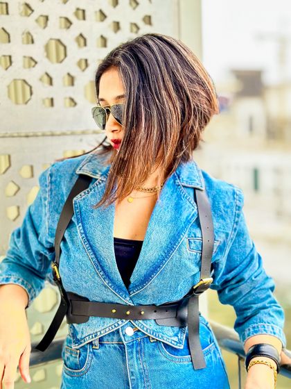 A close-up of the denim blazer and harness belt combination. The details make this look chic and clean.