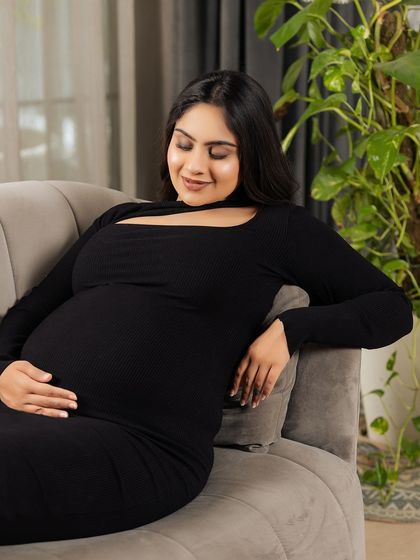 A close-up of the mother-to-be on her sofa, a gentle smile on her face as she looks down at her belly. This is a perfect example of a warm, candid moment captured at home.