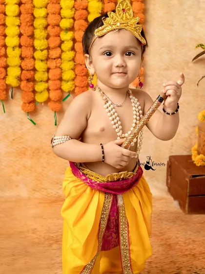 A close-up portrait of a charming little Krishna holding his flute. The detailed costume and traditional jewelry complete the look perfectly.