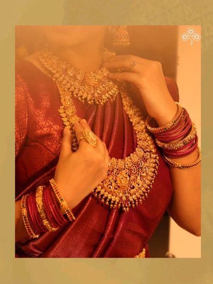 A detailed shot of the layered necklaces against the rich red saree.