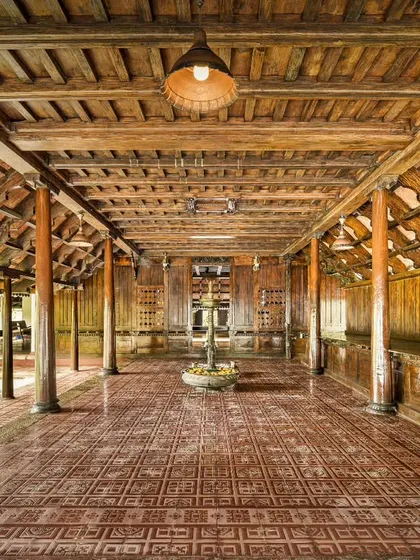 The grand hallway of the Aranmula Palace, with its polished terracotta floors and rows of wooden pillars. This perspective shows the scale and architectural beauty of this restored royal building.