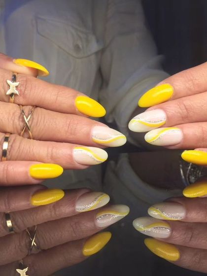 A full view of the cheerful yellow and white swirl nail art.