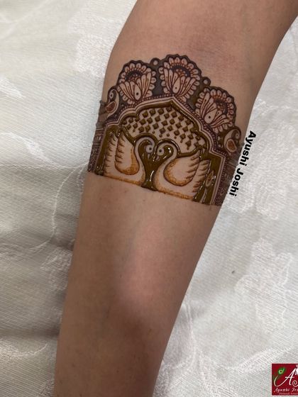 A startup detail of an engagement arm band, featuring two swans inside a traditional arch, symbolizing love and purity.