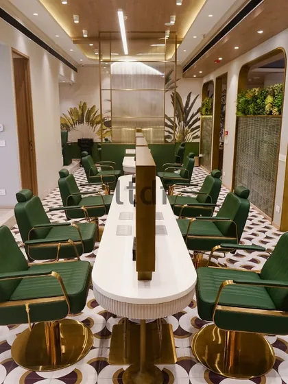 The main styling area at Looks Salon, designed for a communal yet personal experience. The long central station allows for interaction, while the individual mirrors and lush green chairs provide a sense of private luxury for each client.