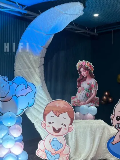 A dreamy moon-themed baby shower or naming ceremony setup with cute baby character cutouts.