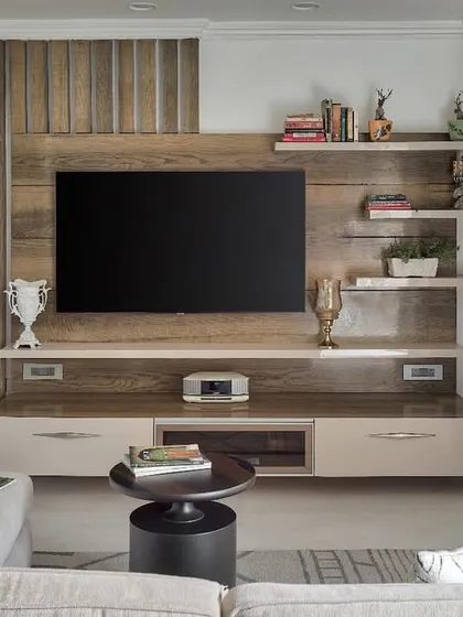 The TV unit at The Classic Modern Storey is a timeless design in beige and brown. It makes a statement when the screen is off but blends seamlessly when it's on, with integrated shelves for personal mementos, ensuring the piece is both functional and personal.