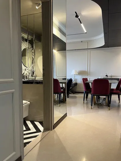 A passage of reflections at the Rustomjee Paramount project. I used mirrored walls to visually expand the space and create intriguing views into the dining area, which features bold red velvet chairs.