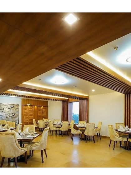 The restaurant interior at our Calicut hotel project. We used a combination of wood ceiling details, recessed lighting, and plush upholstered chairs to create a comfortable and upscale dining environment.