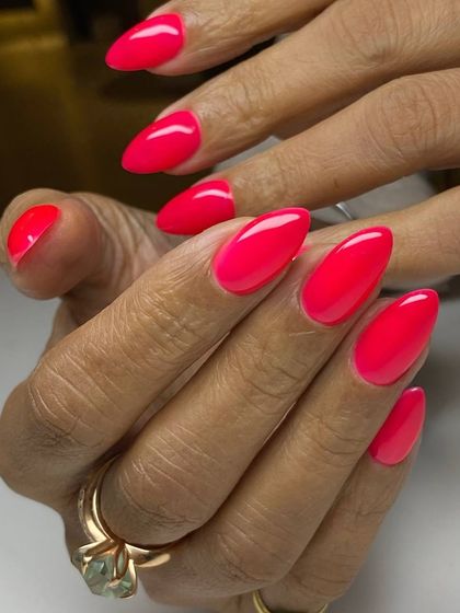 A vibrant, neon-pink manicure on almond-shaped nails. This bold and energetic color is perfect for those who aren't afraid to stand out.