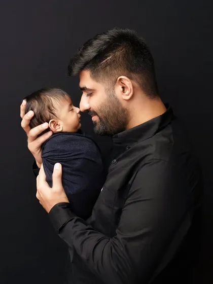 A father and his newborn son, nose to nose. This intimate, close-up portrait against a dark background is powerful and full of emotion.