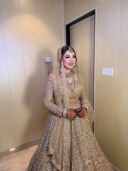 A full-length portrait of the Walima bride. Her gold gown sparkles, and her makeup is designed to look flawless all evening long.