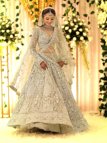 The bride looking down with a gentle smile, giving a full view of her gorgeous outfit and the sparkling jewellery that completes it.