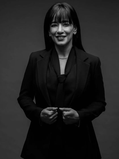 A classic black and white headshot that exudes professionalism. The lighting is crafted to be flattering yet strong, highlighting her expression and creating a timeless image for her brand.