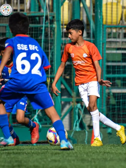 A young player stays focused on the ball while under pressure from an opponent. Mental toughness is a key part of our curriculum.