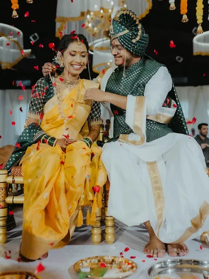 A joyful moment during a Maharashtrian wedding, with the groom tying the mangalsutra, surrounded by falling petals.
