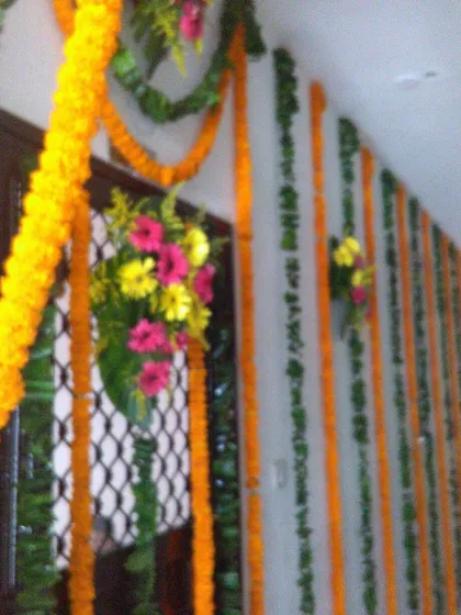 For decorating long corridors or walls in a flat, we use vertical strings of marigold and mango leaves. This is a simple, cost-effective way to make a large space feel festive for any event.