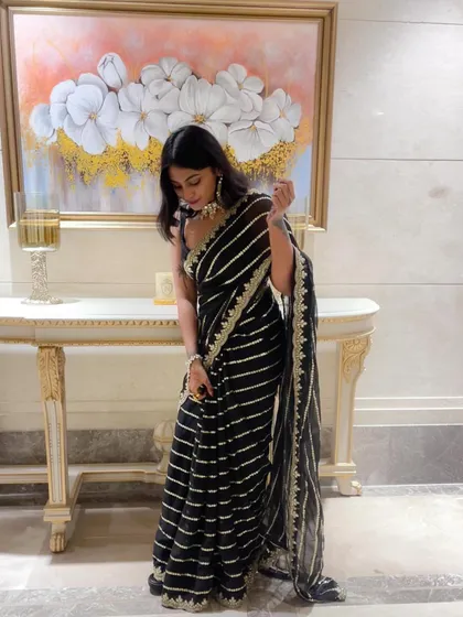 A posed shot showing the full elegance of the black striped saree. Paired with a simple black blouse, the saree itself becomes the main focus.