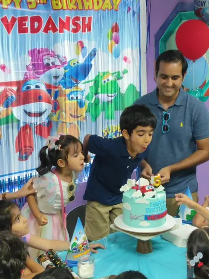 The big moment! Here, the birthday star, Vedansh, is surrounded by friends and family as he blows out the candles on his amazing Super Wings themed cake. We create a special space for these cherished memories.