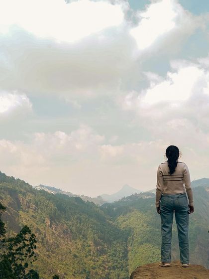 A woman stands on a cliff edge, looking out at the misty hills of Kodaikanal. It's a powerful image of solitude and soaking in the grandeur of nature.