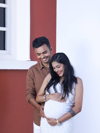 A tender moment between an expecting couple during their outdoor shoot. The father-to-be gently holds the baby bump, sharing a smile with his partner.
