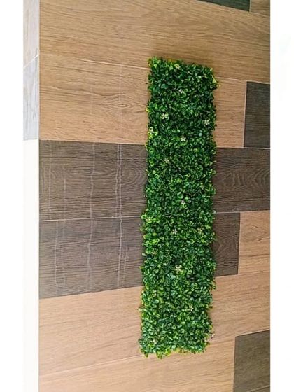 A single panel of our artificial boxwood matting against a tiled wall. This shows the beginning stages of a creative wall decor project.