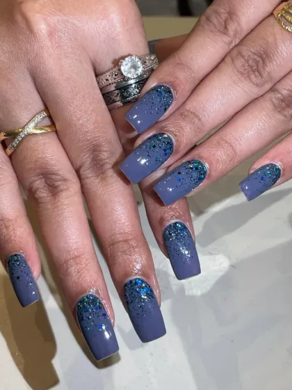 A moody blue-grey base with a cascade of blue glitter from the cuticles.
