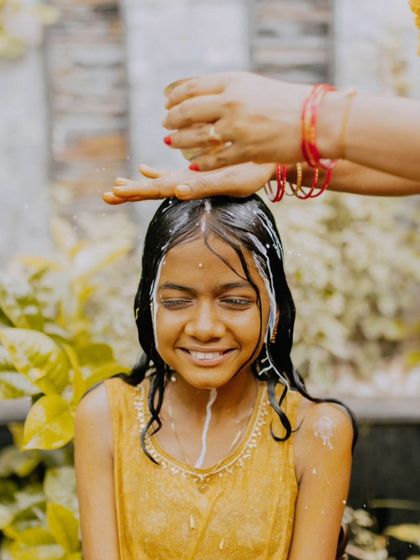 A portrait of a young woman during her Mangala Snaanam, with milk being poured as part of the ritual.