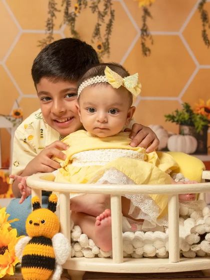 A loving big brother with his little sister in our sunflower-themed setup. The warm yellow tones create a happy and vibrant atmosphere.