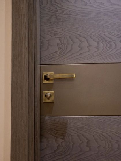 A detail shot of the door handle and lock on the grey wood veneer door, showcasing the quality of the hardware I use.