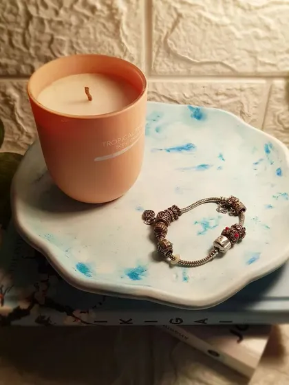 The round concrete plate tray used as a candle stand. The cool blue tones of the tray contrast nicely with the warm peach candle.