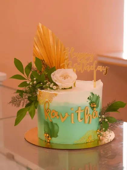 Pastels and gold make for a stunning combination. This cake features a pastel green watercolor finish with a honeycomb stencil effect, decorated with lush greenery, a white rose, and a golden palm spear.