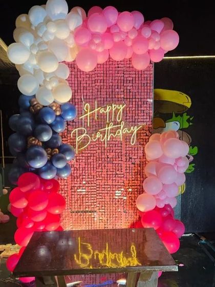 A vibrant balloon frame around a pink shimmer wall. This backdrop uses multiple shades of pink, white, and dark blue balloons to create a bold and eye-catching photo corner for any birthday party.