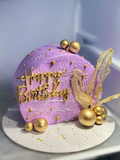 A modern "top forward" cake design in a beautiful lavender shade. This trendy style is decorated with gold spheres and delicate rice paper sails.