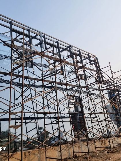 Scaffolding surrounds the glass facade of the Experience Center. This phase is critical for installing the large glass panels that define the building's transparent volume.