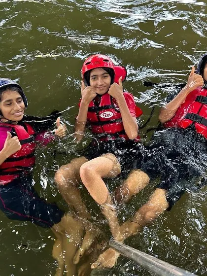 Three participants give a thumbs-up while floating in the water, enjoying their summer camp experience to the fullest.