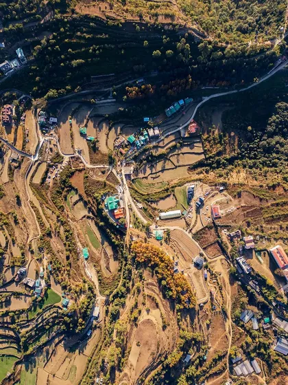 An aerial view of the terraced farms and winding roads in the hills surrounding Naukuchiatal.