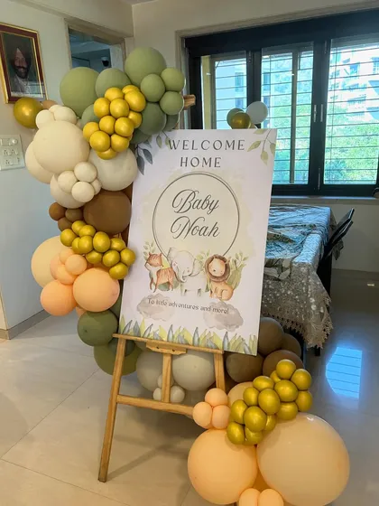 A personalized 'Welcome Home Baby Noah' sign with cute safari animals, framed by a beautiful balloon arrangement.