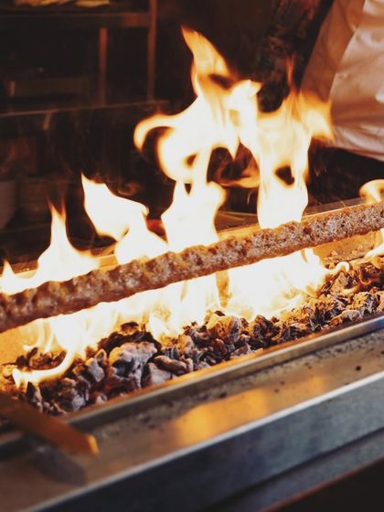 The heart of my Turkish kitchen. Here, a massive Adana kebab is grilled over open flames, a testament to our commitment to authentic cooking methods and bold flavors.