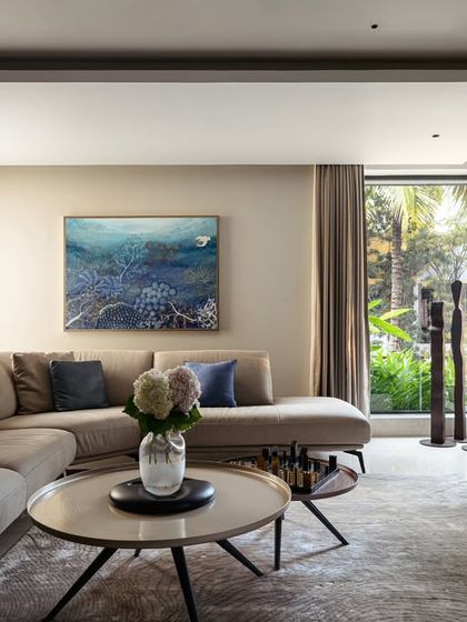 The family lounge in Villa Aish is a comfortable and elegant space with direct views of the garden. The neutral color palette is accented with deep blues and natural textures, creating a calm environment that connects with the outdoors.