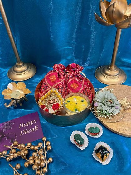 A traditional yet elegant Diwali gift set in a brass bowl. This hamper includes decorative potlis, a floating candle, and beautifully crafted sweets, perfect for festive greetings.