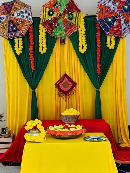 A simple yet elegant table setup for a Mehendi function. I used a combination of yellow, green, and red drapes, with Rajasthani umbrellas and marigold garlands to create a festive corner for placing Mehendi cones and other items.