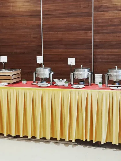 A simple and elegant buffet setup against a wood panelled wall, perfect for a corporate meeting or seminar. The focus is on clean lines and efficient service.