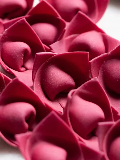Beautiful, rose-shaped beetroot pasta. The vibrant color and unique form are highlighted in this artistic macro photograph.