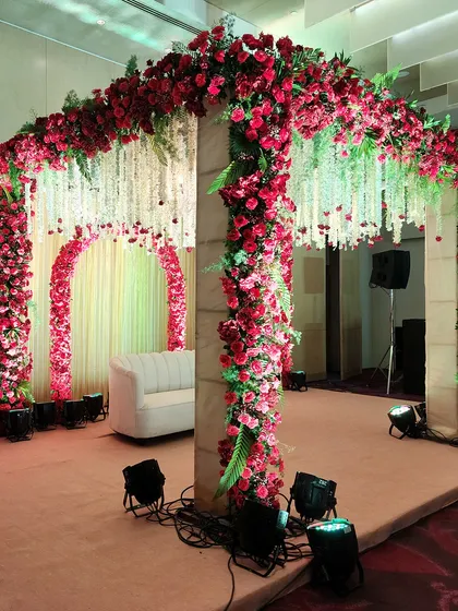 A side view of the magnificent red floral mandap, showing the structural detail and the density of the rose arrangements. The hanging floral strings add another layer of texture and tradition to the design.