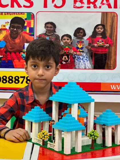 A student presents his elegant LEGO gazebo structure with a blue-tiled roof.