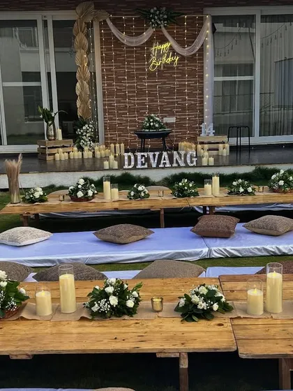 The birthday backdrop for the outdoor movie night, featuring a neon sign, candle lighting, and rustic elements.