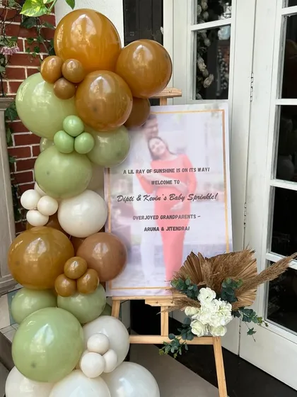 We create personalized welcome signs that match the event's theme. This one, framed by a matching balloon garland, warmly greets guests to the baby sprinkle.