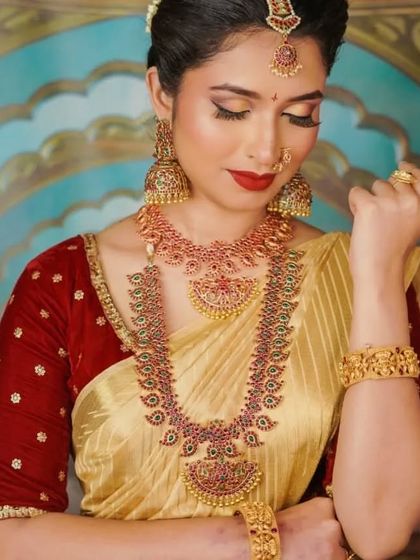 A model looking graceful in our full kemp stone bridal set, paired with a classic gold and red silk saree.