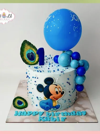 A unique Mickey Mouse cake for Kabir's first birthday, combining the classic character with elegant peacock feathers and a blue balloon cascade.
